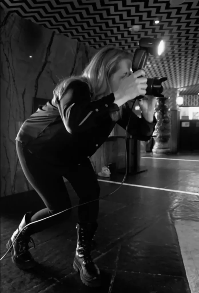Zwart-witfoto van een fotografe die geknield op een podium een foto maakt