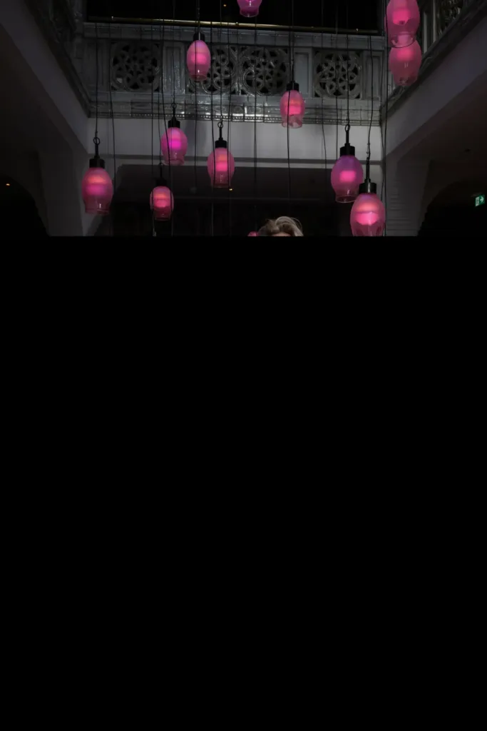 Hanglampen in verschillende tinten roze verlichten een stijlvolle ruimte met een moderne uitstraling.