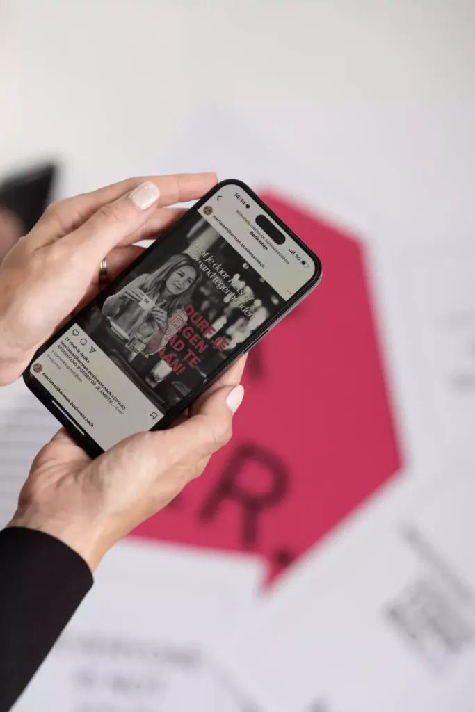 Een hand houdt een smartphone met een Instagram-post over zelfvertrouwen en persoonlijke groei, op een kleurrijke achtergrond.