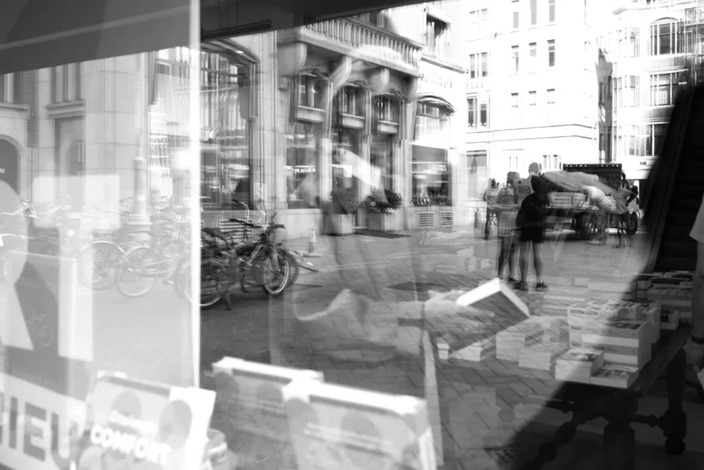 Straat met een voorbijganger, vaag zichtbaar in de weerspiegeling van een etalageruit.